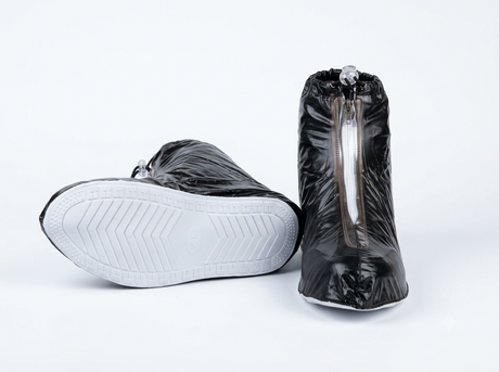 Black waterproof shoe covers worn over shoes on a rainy street